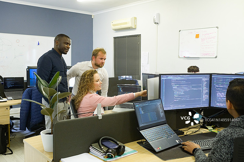 多元种族计算机科学家在办公室与同事讨论工作，屏幕上显示代码图片素材