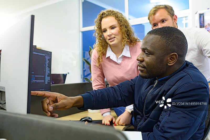 计算机科学家与同事讨论工作，指向屏幕图片素材