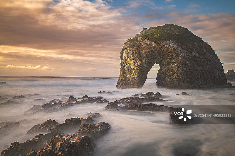 壮丽天空与独特海岸岩层映衬下的金色日出海景图片素材