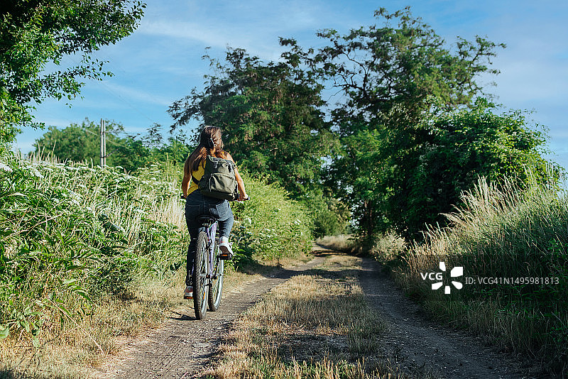 阳光明媚的日子里在公园骑自行车的女孩图片素材