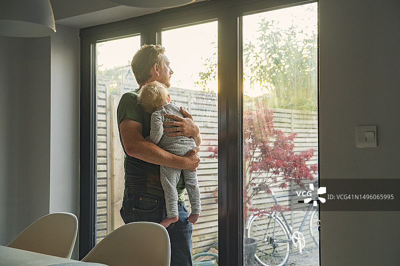 中年父亲抱着睡着的女儿，眺望着花园图片素材