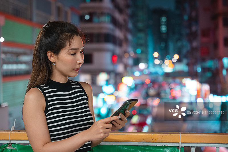 亚洲女人在香港夜景中使用智能手机图片素材
