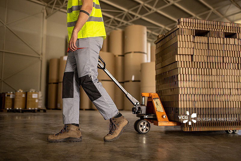 推着装有瓦楞纸板的托盘车的年轻男人图片素材