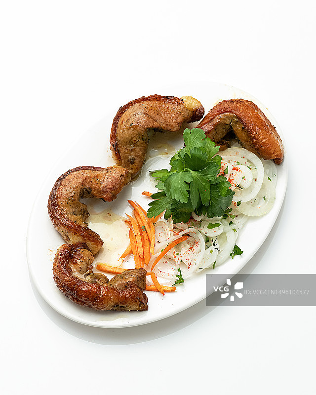 洋葱胡萝卜鸭肉串：白色盘子上搭配的烤肉块和蔬菜，以欧芹装饰，中东美食图片素材