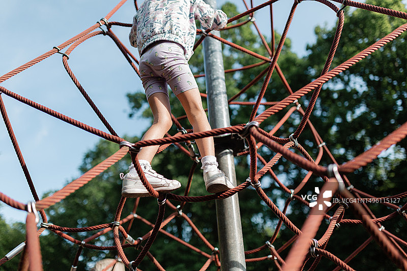 晴天女孩在游乐场爬攀爬网图片素材