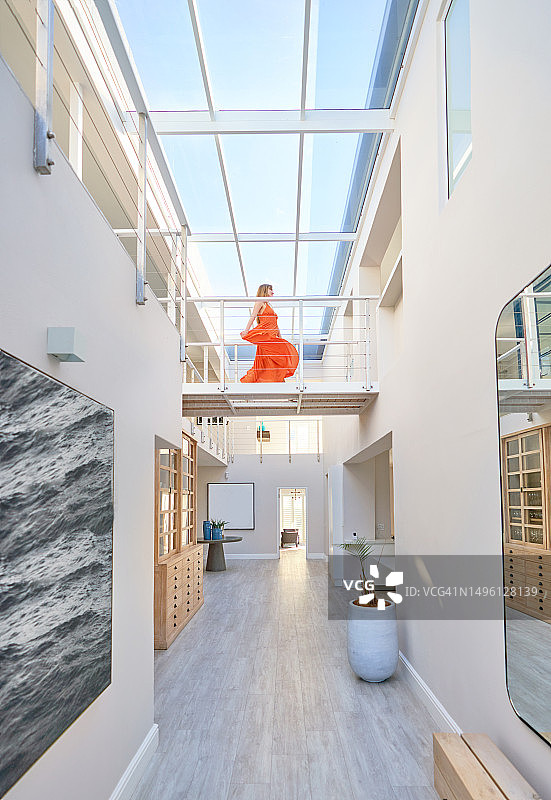 穿着橙色连衣裙的女人走在现代住宅的T台上图片素材