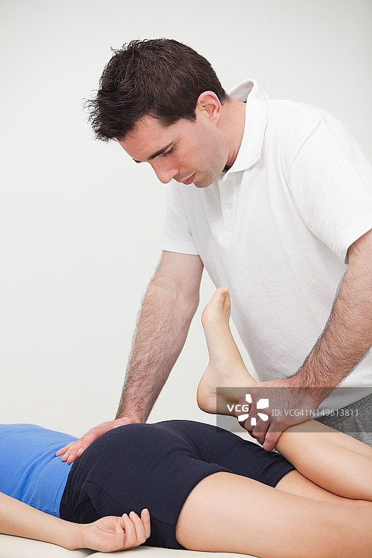 医生站立时拉伸妇女的腿图片素材