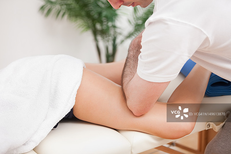 理疗师用肘部为女性按摩大腿图片素材