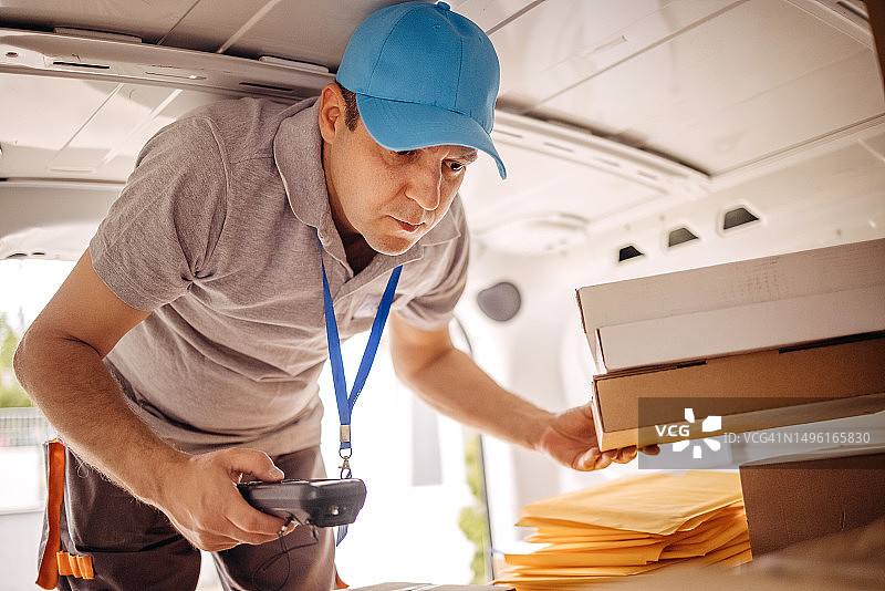 快递员使用扫描仪查找要递送的包裹图片素材