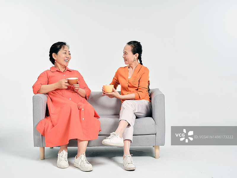 坐在沙发上愉快聊天的两位老年妇女（影棚拍摄）图片素材