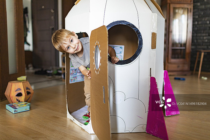 小男孩在自制纸板火箭中玩耍图片素材