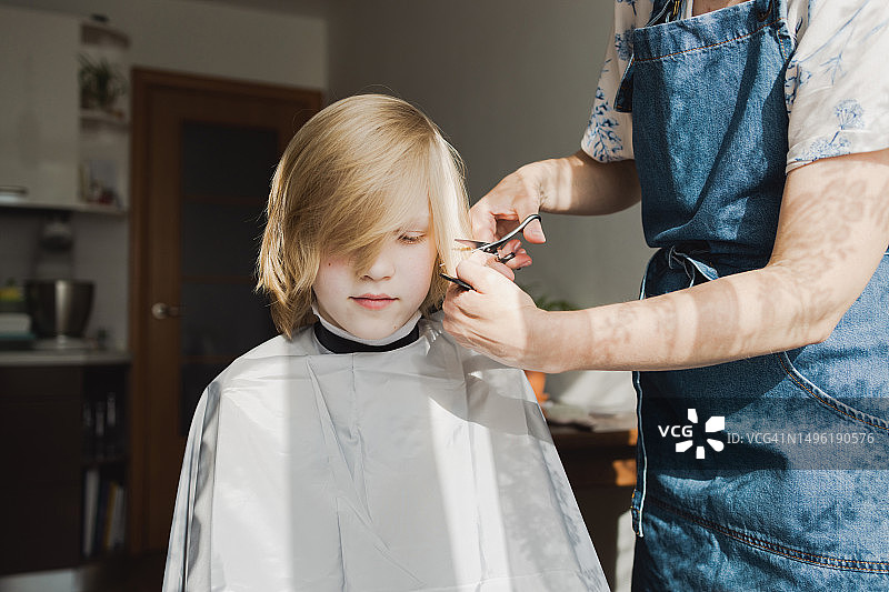 母亲在厨房给十几岁的儿子理发图片素材