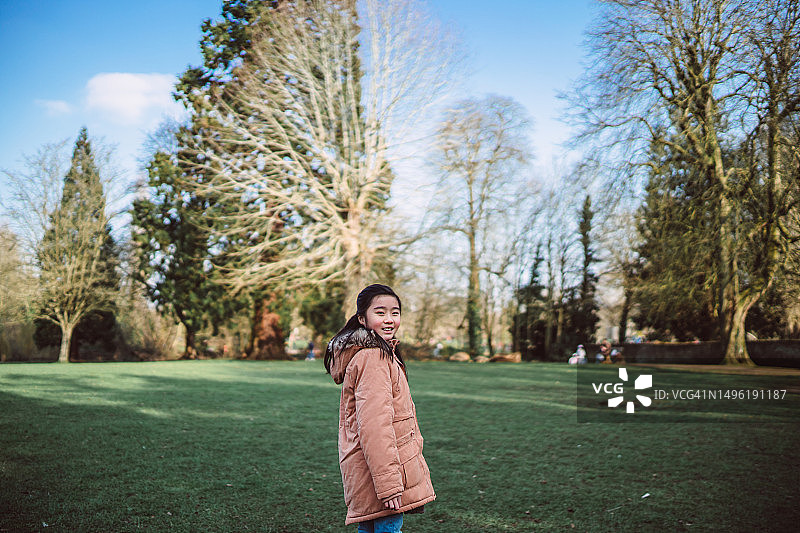 可爱女孩在阳光明媚的早晨在公园里散步，对着镜头高兴地微笑图片素材