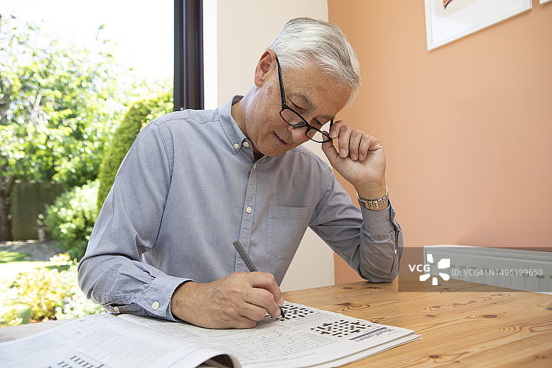 成熟男人在家中玩填字游戏图片素材