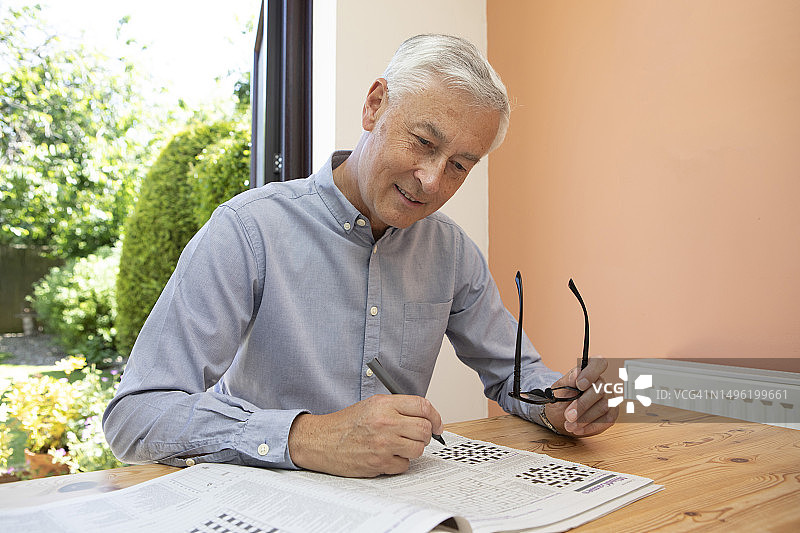 成熟男人在家中玩填字游戏图片素材