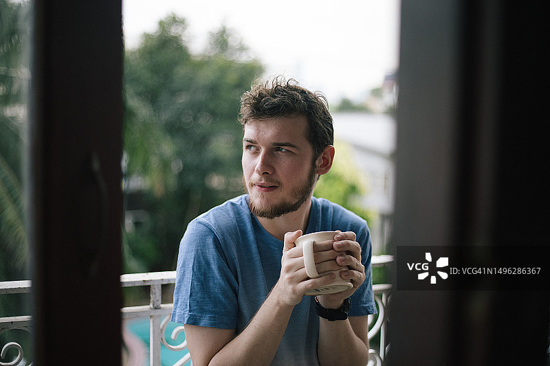 胡须男在阳台上喝咖啡图片素材