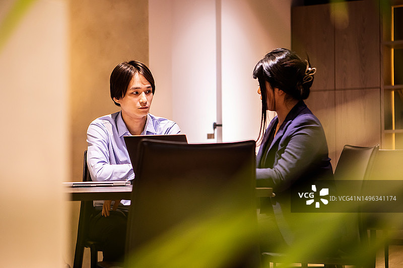 男人专注地倾听被邀请到他公司的女性顾问讲话。图片素材