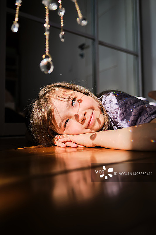 穿着紫色连衣裙躺在木地板上的7岁女孩图片素材