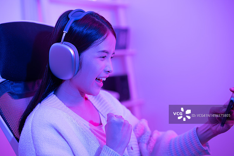 用智能手机直播玩游戏的年轻微笑女人图片素材