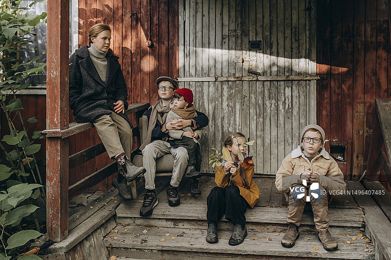 一家人坐在破旧小屋的门廊上图片素材