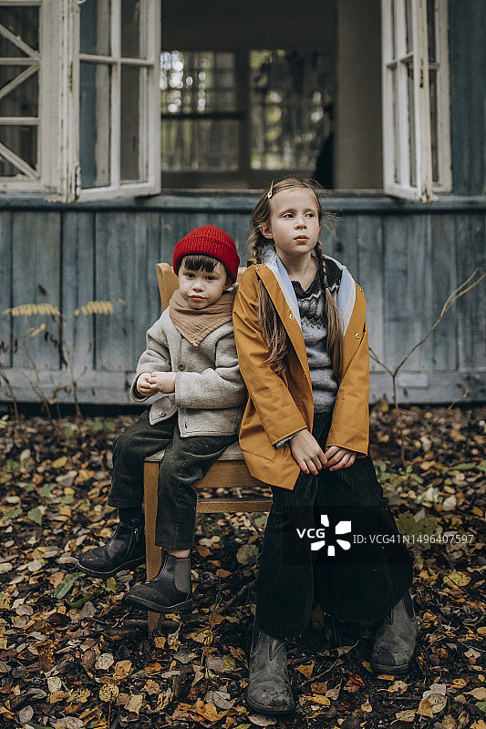 兄妹坐在废弃小屋的椅子上图片素材