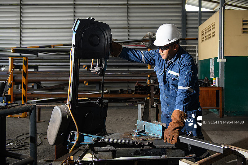 重工业工人用电动带锯机切割钢材图片素材