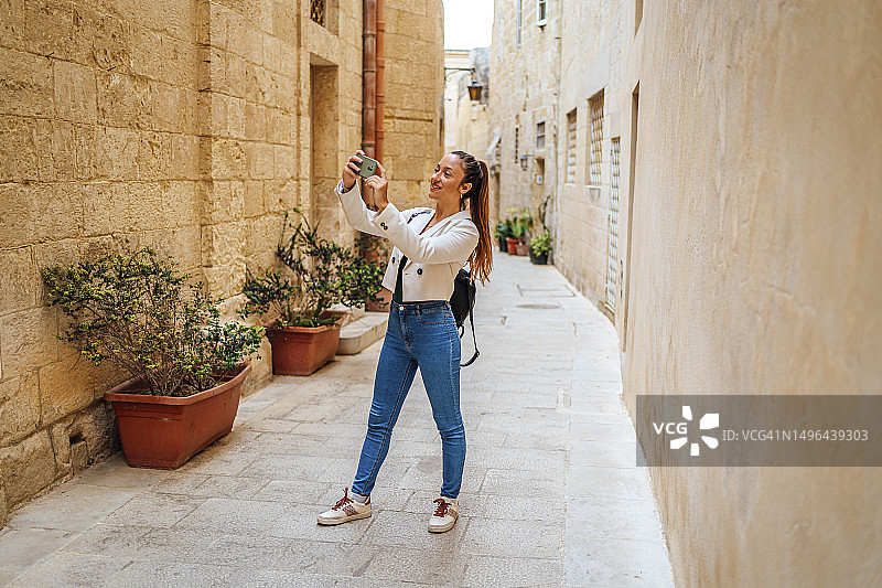 在马耳他姆迪纳拍照的年轻女游客图片素材