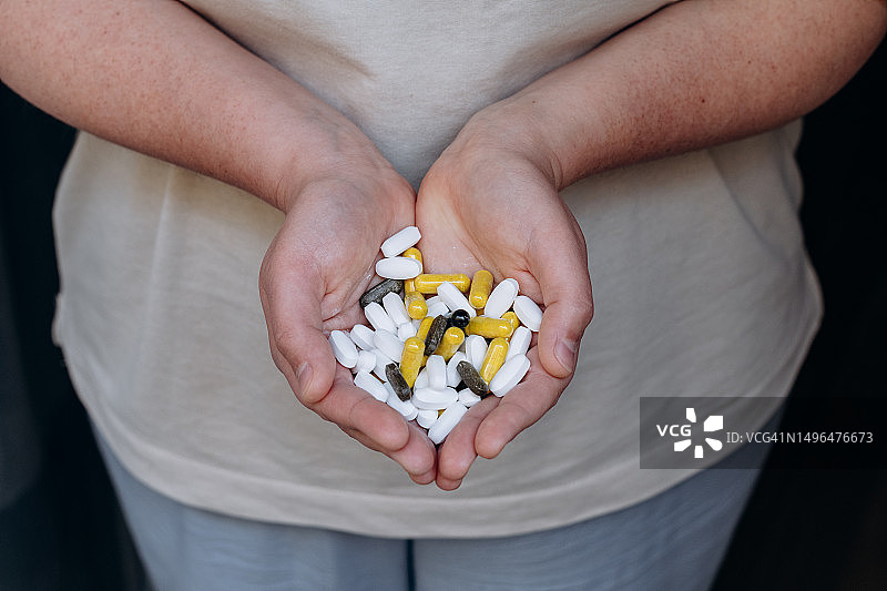 妇女服用她的维生素和补充剂，各种药丸和胶囊图片素材