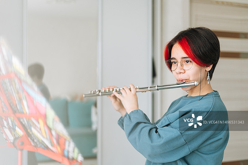 在家中儿童房吹长笛的短发少女，孩子在做音乐作业图片素材
