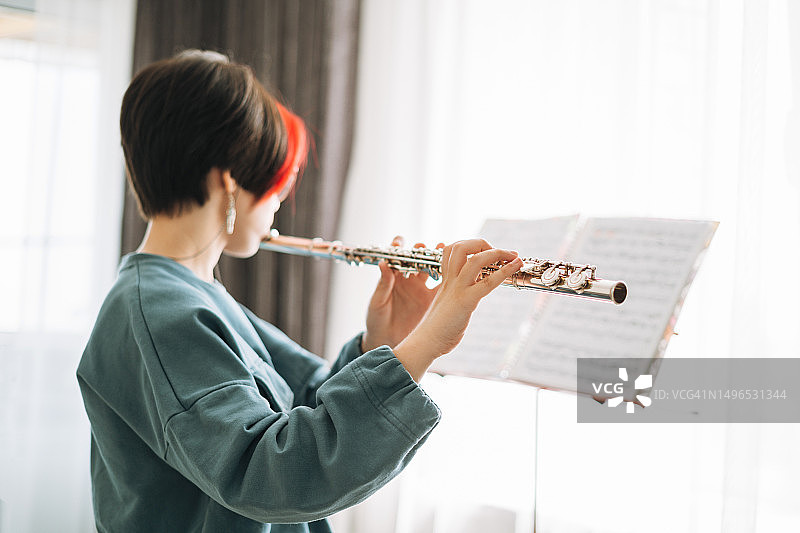 在家中儿童房吹长笛的短发少女，孩子在做音乐作业图片素材