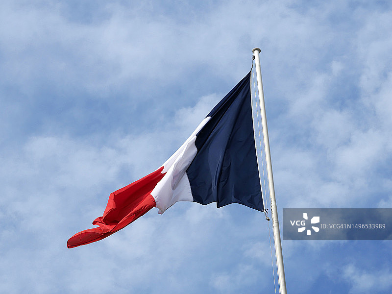 在多云的天空背景下，法国国旗在暴风雨中飘扬图片素材