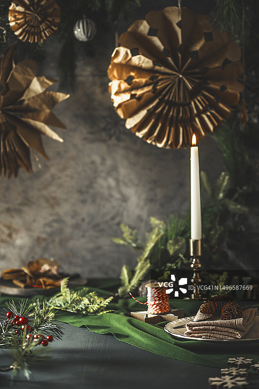 舒适的圣诞静物：绿色桌子上燃烧的复古烛台和餐具摆设图片素材