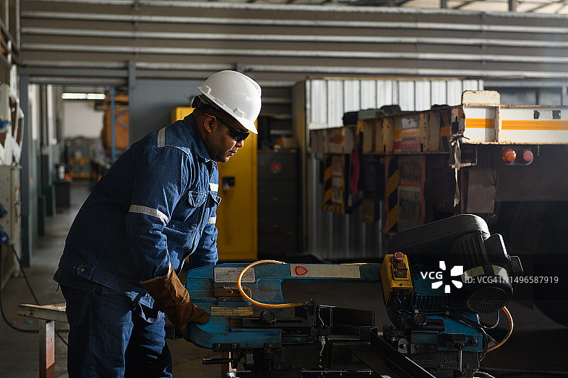 重工业工人用电动带锯机切割钢材图片素材