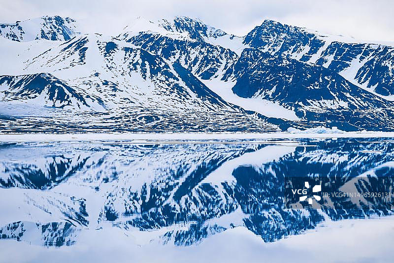 斯瓦尔巴群岛岩石海岸的雪山倒影图片素材