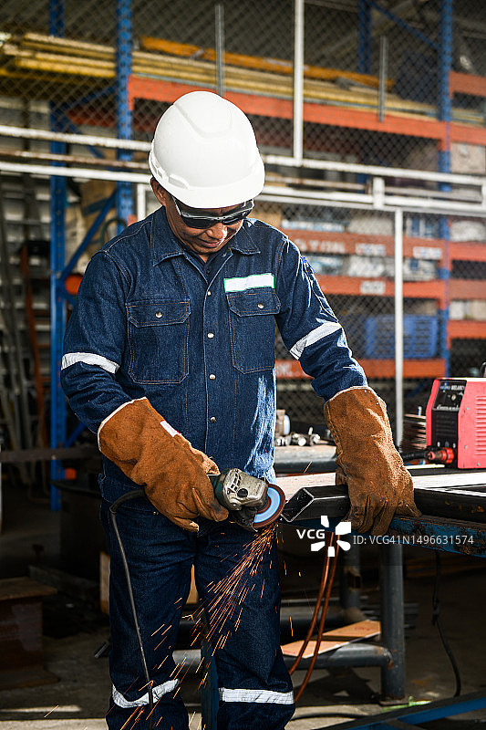 重工业工人用角磨机切割钢材图片素材