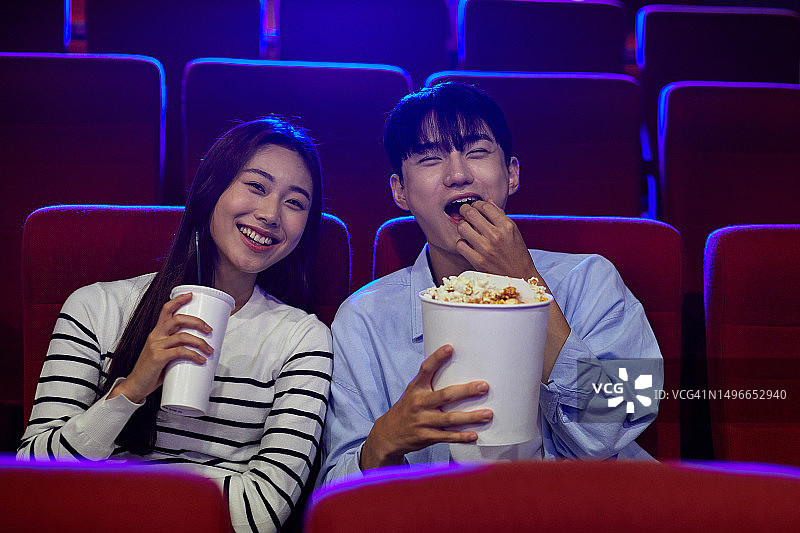 20多岁的情侣在电影院约会吃爆米花图片素材