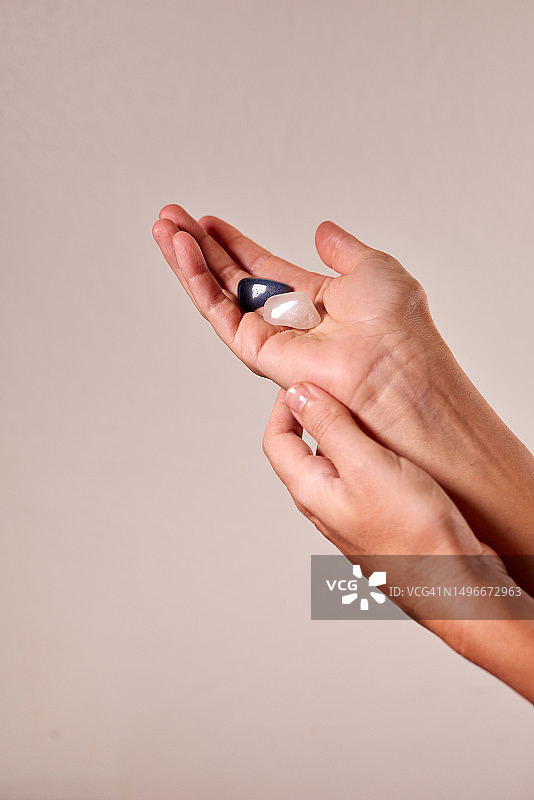 女人温柔地捧着两颗抛光的玫瑰石英和昆赛石宝石图片素材