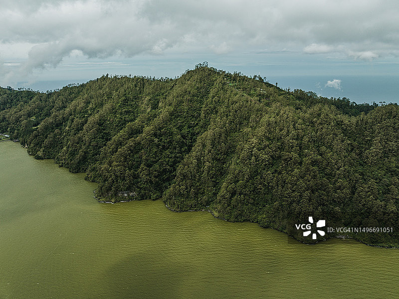 巴厘岛巴图尔湖边的树木覆盖的悬崖航拍图片素材