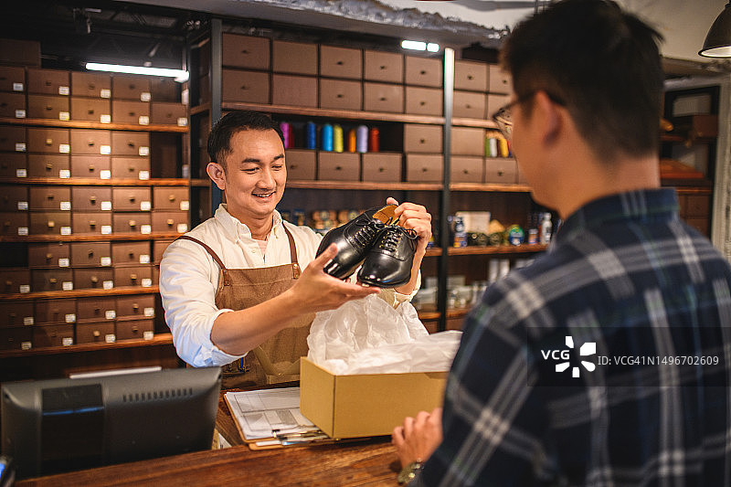 年轻男店员在精品店内向顾客销售正装鞋图片素材