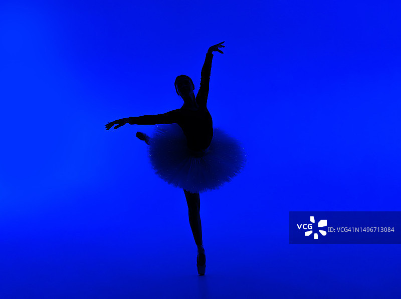 在蓝色背景下跳舞的芭蕾舞者全身照图片素材
