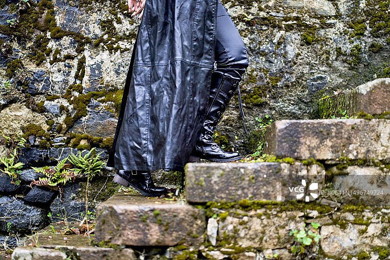 穿黑色夹克爬梯子的女人腿部侧视图图片素材