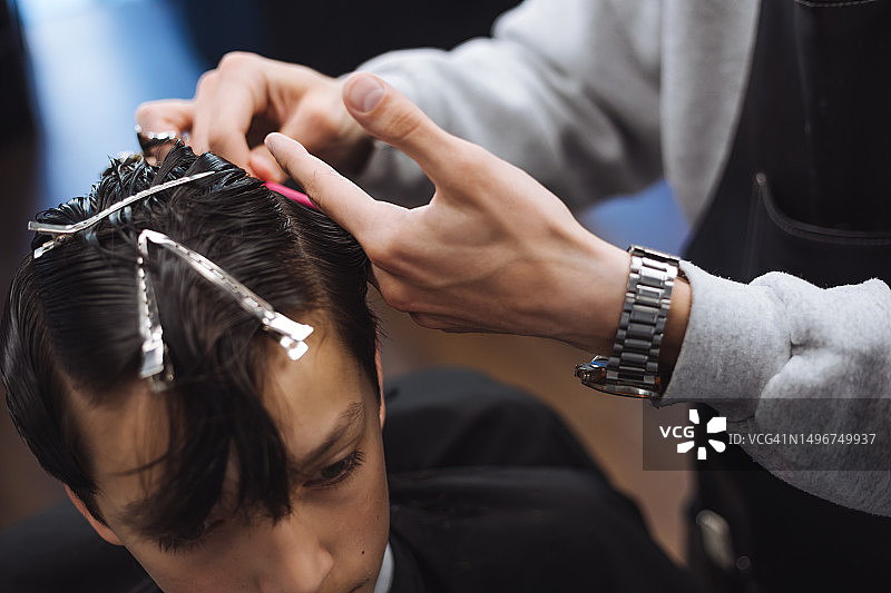 在理发沙龙里，熟练的男理发师为男顾客理发图片素材
