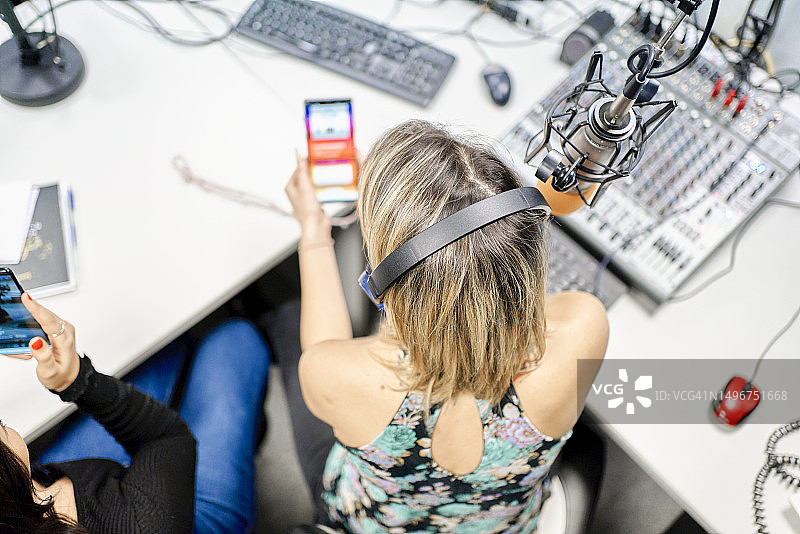 广播电台主持人与同事在办公桌旁打电话的鸟瞰图图片素材