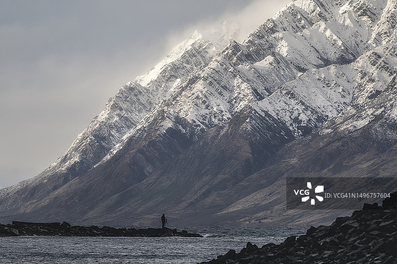 新西兰：站在湖岸边仰望雪山的男子图片素材
