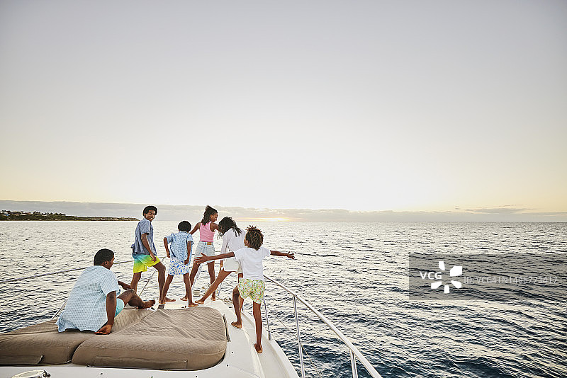 日出时分，姐弟在游艇船头嬉戏图片素材