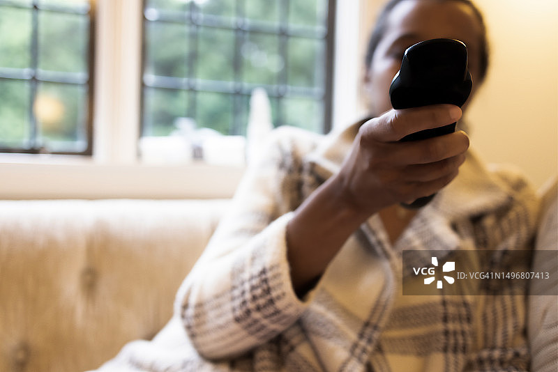 黑人女性拿着遥控器看电视图片素材