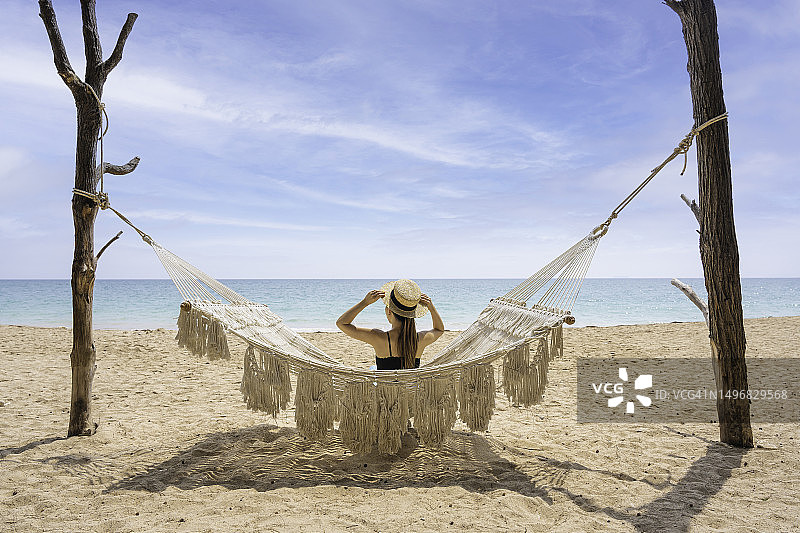 女子坐在沙滩吊床上的背影图片素材