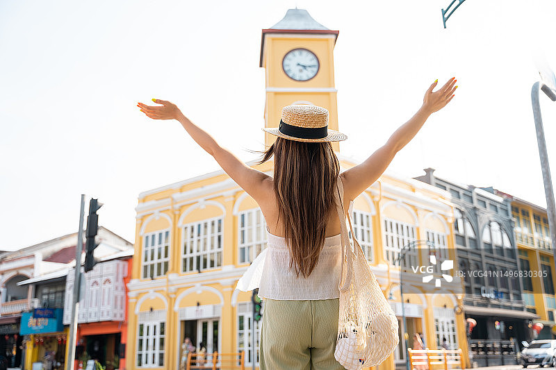 戴着遮阳帽在普吉岛中葡风格建筑前旅行的亚洲女人图片素材
