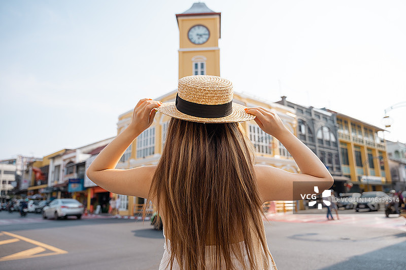 戴着遮阳帽在普吉岛中葡风格建筑旁旅行的亚洲女子背影图片素材