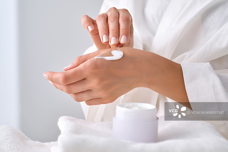女人拿着一罐白色面霜图片素材